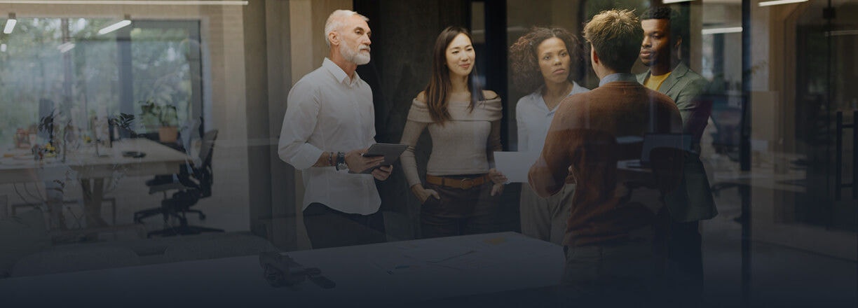 Um grupo de colegas discutindo um projeto ao redor de uma mesa em um escritório moderno.