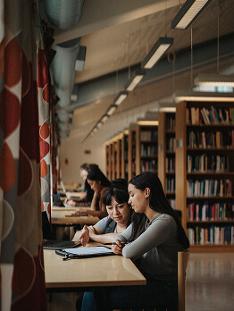 Estudantes estudando juntos em uma mesa em uma biblioteca.