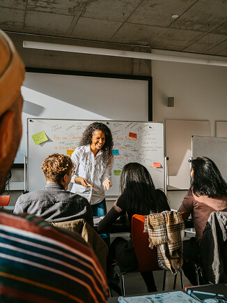 Um instrutor apresentando uma aula aos alunos em uma sala de aula com um quadro branco.